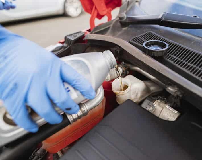 Mechanic applying brake fluid to a car for automotive servicing and repair