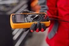 Person holding a digital multimeter purchased from NSJ Wholesale for electrical testing