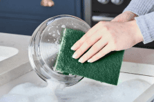 Using a scouring pad to clean dishes and kitchen surfaces in South Africa