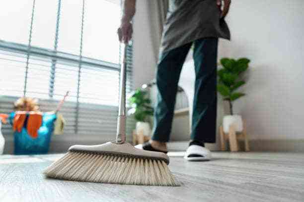 Person using a broom to clean a household floor in South Africa